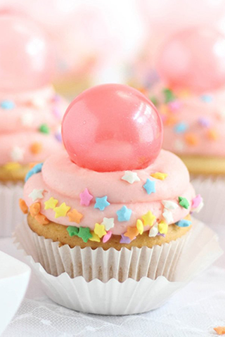 Pink cupcake covered in sprinkles and topped with a sugar orb
