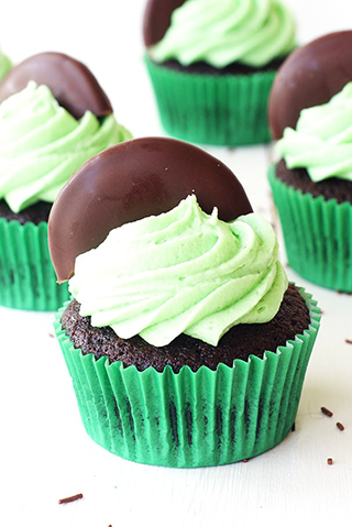 Chocolate cupcakes with mint green icing and half a chocolate dipped cookie on top
