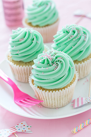White cupcakes frosted in light green cicing with pink sprinkles
