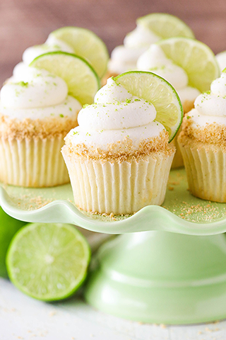 Lime cupcakes frosted in white icing with graham cracker crumbs around the middle and a thin slice of lime on top