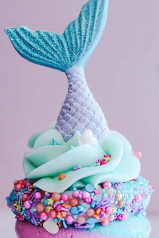Pink and blue cupcake frosted in light blue icing with rainbow sprinkles and a sculped, shimmering mermaid tail on top