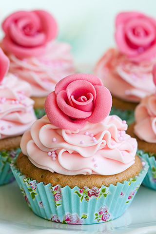 Golden cupcake frosted in light pink, with pink sprinkles and a dark pink sculpted rose